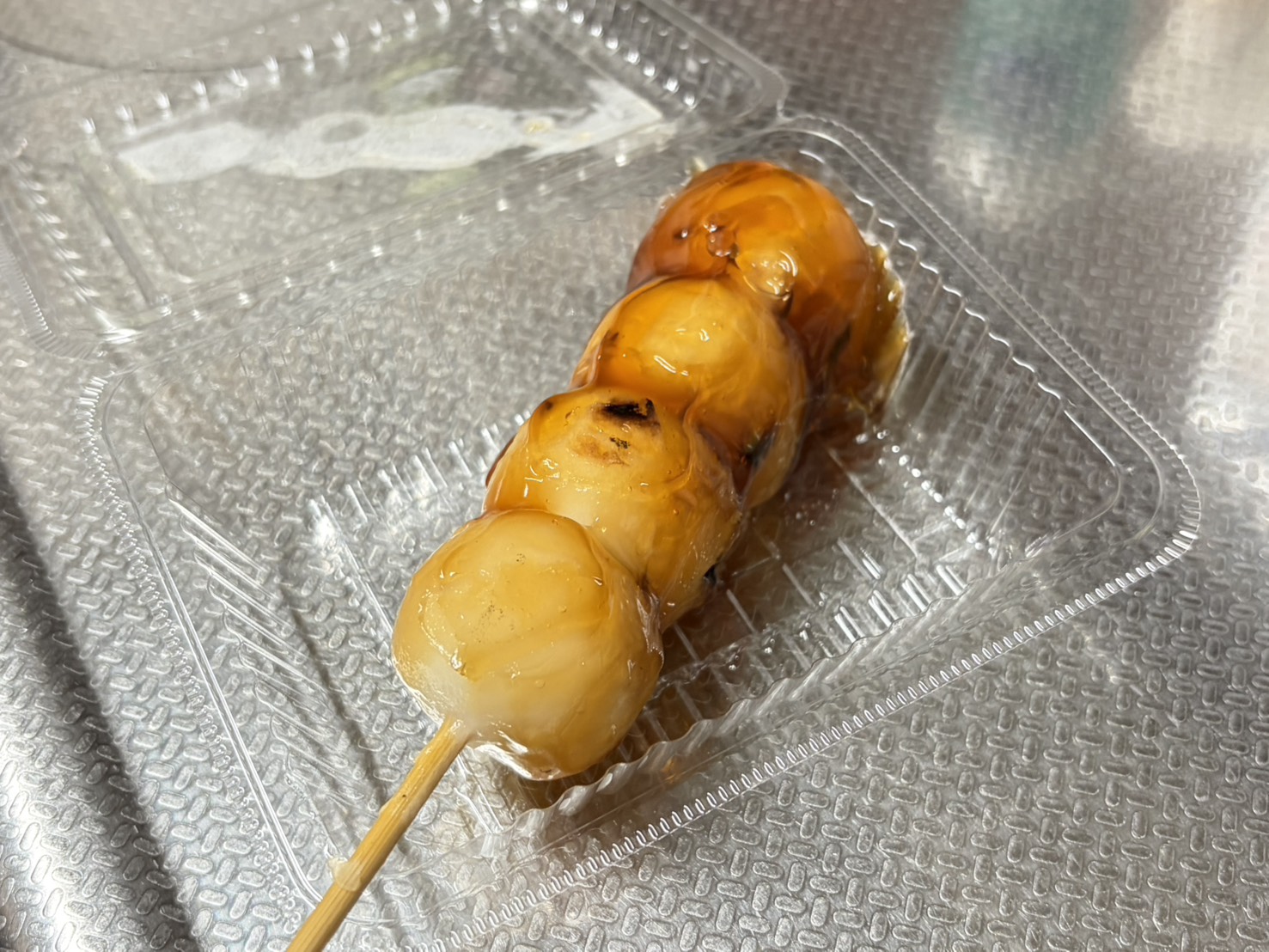 つやのあるタレがかかった、4つの団子が刺さったみたらし団子
