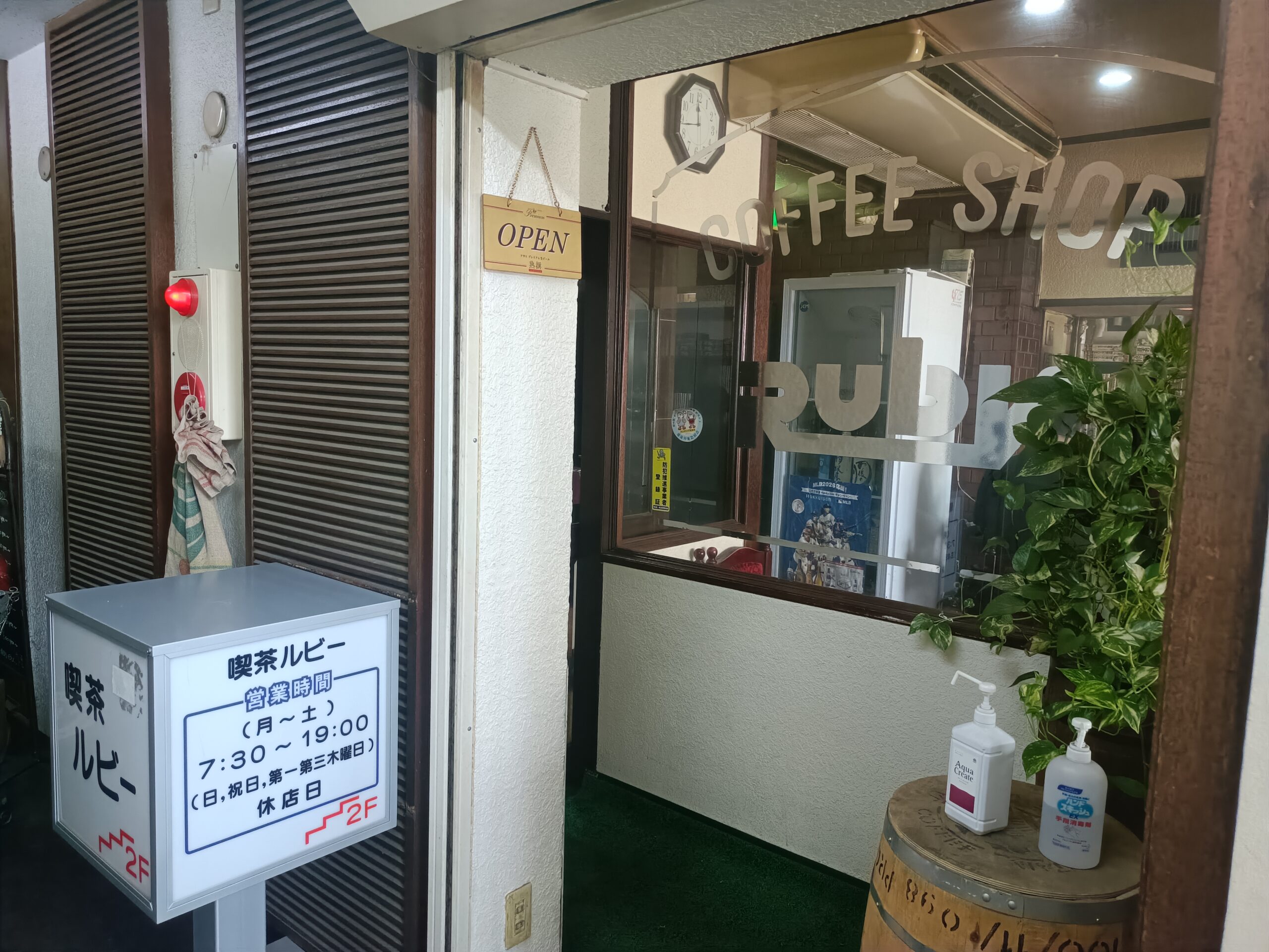 喫茶ルビーの入口。営業時間と休店日を記した看板が立つ