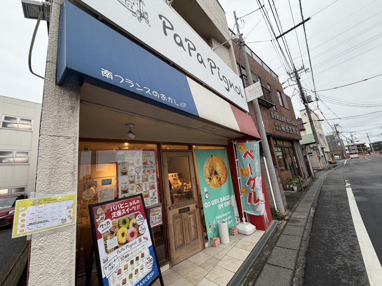 白い看板に「PaPa Pignol」と書かれた店舗外観。トリコロールのひさしが目印