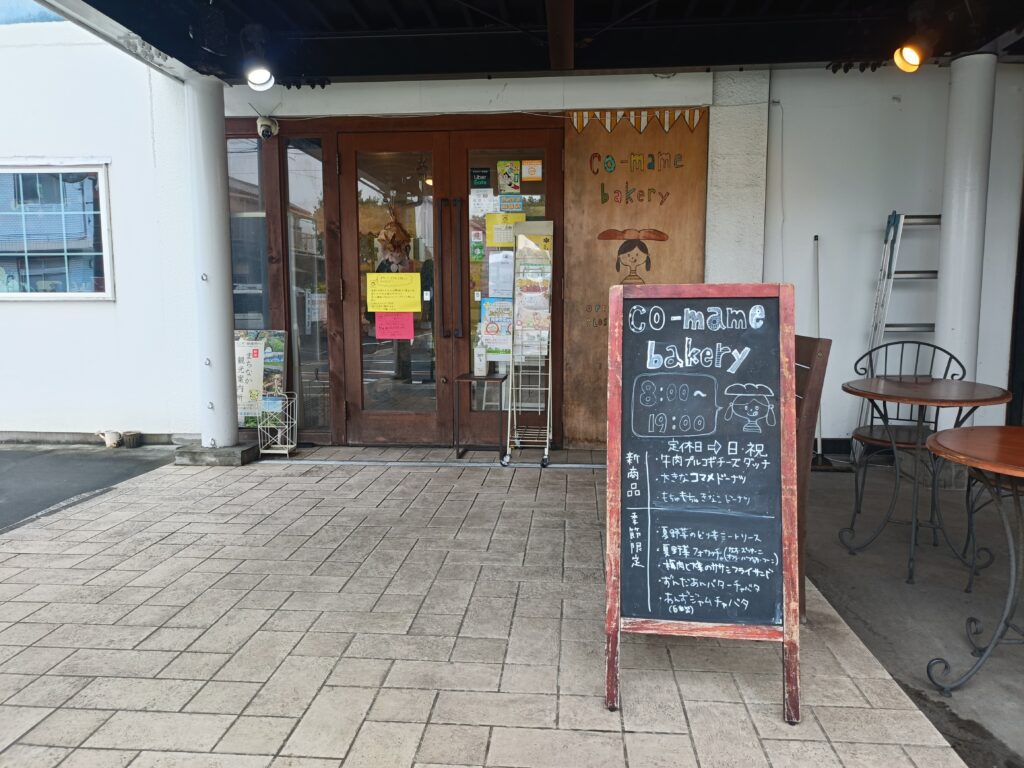 黒板メニューが置かれたco-mame bakeryの店先。テーブルとイスがある