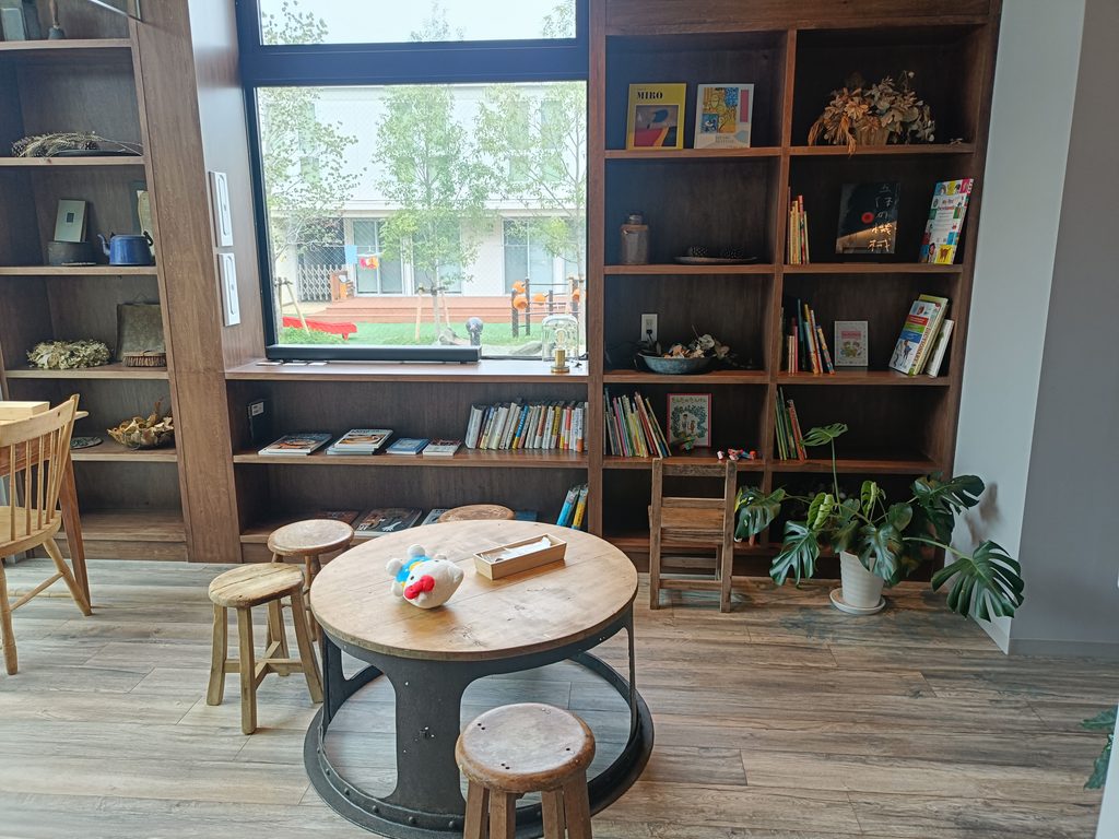 絵本が並ぶ本棚と丸テーブル、小さな椅子のある店内